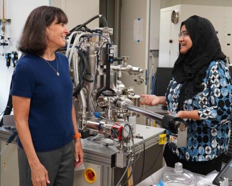 Stacey Bent and Sanzeeda Baig Shuchi standing beside an X-ray photoelectron spectroscopy setup in a Stanford lab.