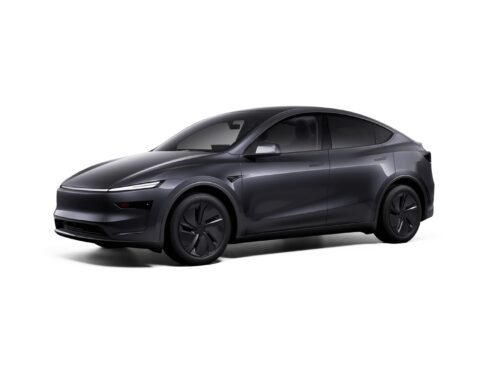 Front three-quarter view of a white Tesla Model Y Performance featuring redesigned bumpers, carbon fiber spoiler, and 21-inch Arachnid wheels against a plain white background.