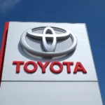 A large white and red Toyota dealership sign against a blue sky.