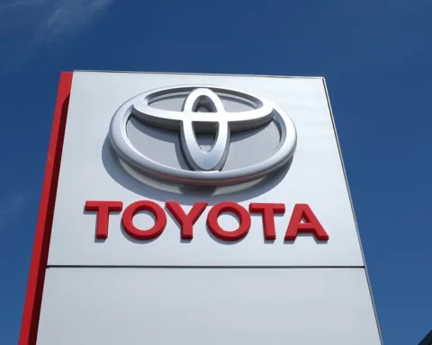 A large white and red Toyota dealership sign against a blue sky.