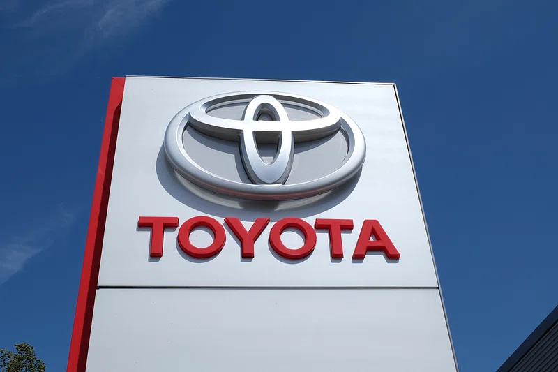 A large white and red Toyota dealership sign against a blue sky.