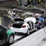 A car factory production line in General Motors Manufacturing Poland, with several car bodies in various stages of assembly.
