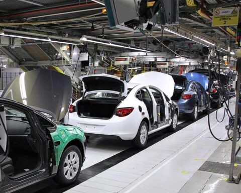 A car factory production line in General Motors Manufacturing Poland, with several car bodies in various stages of assembly.