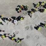 Overhead view of researchers in high-vis around large sauropod footprints at Dewars Farm Quarry, Oxfordshire