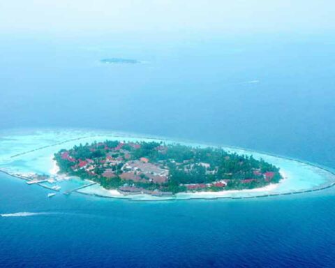 Aerial view of a Maldives resort island with overwater villas and a turquoise lagoon