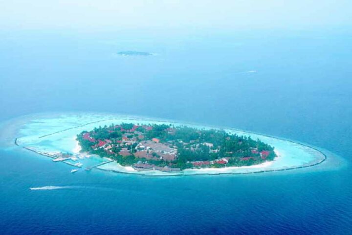 Aerial view of a Maldives resort island with overwater villas and a turquoise lagoon