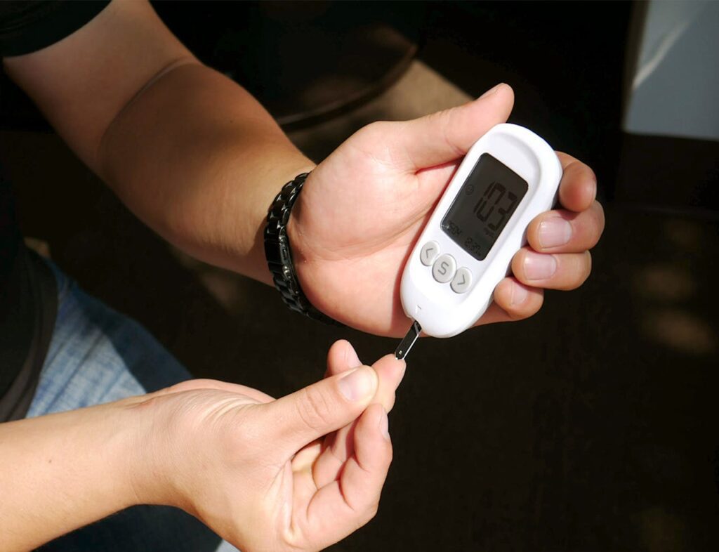 Close-up of hands loading a test strip into a glucometer for a blood sugar check