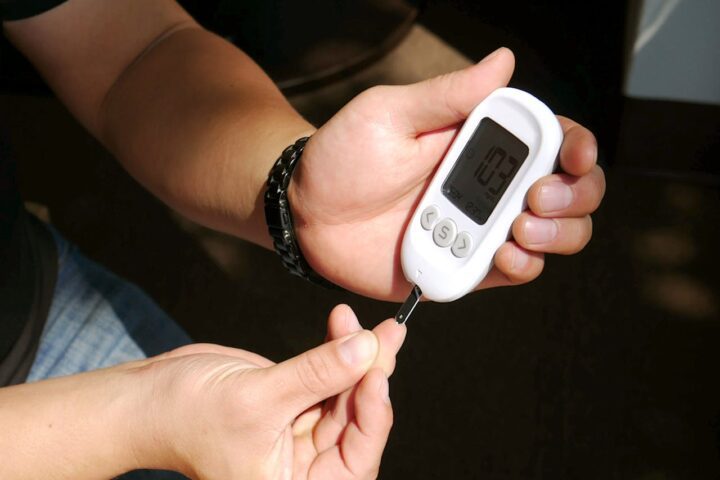 Close-up of hands loading a test strip into a glucometer for a blood sugar check