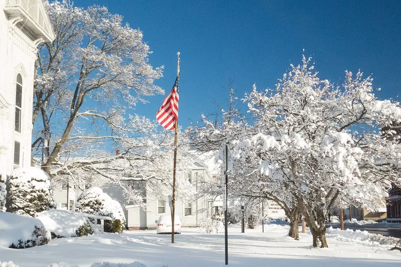 Commuters walking through New York Penn Station during a Thanksgiving travel rush, with directional signs overhead and travelers carrying luggage.