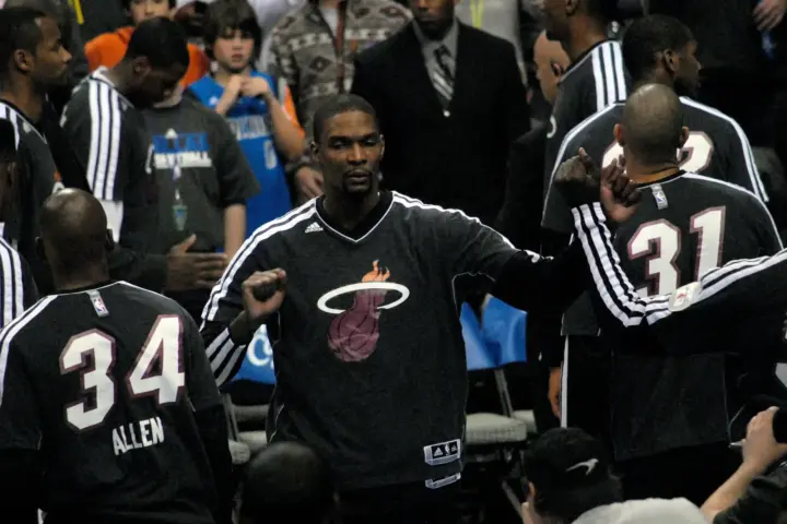 Chris Bosh in a Miami Heat warm-up suit fist-bumping teammates during pregame introductions in December 2012.