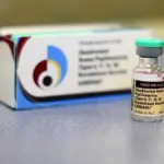 Gardasil HPV vaccine vial placed in front of its packaging box on a clinical surface.