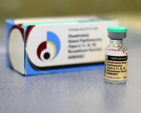 Gardasil HPV vaccine vial placed in front of its packaging box on a clinical surface.