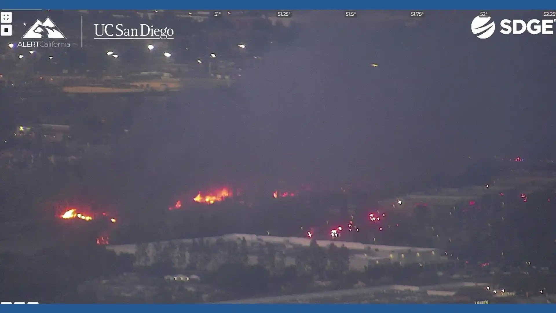 Wildfire burning at night near buildings and roads in San Diego County captured by ALERTCalifornia camera network with emergency vehicles responding