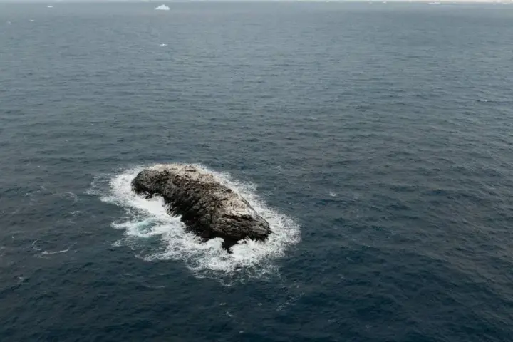 Ice-covered rocky island surrounded by ocean waves in the Weddell Sea, identified during the 2026 AWI Polarstern Antarctic expedition.