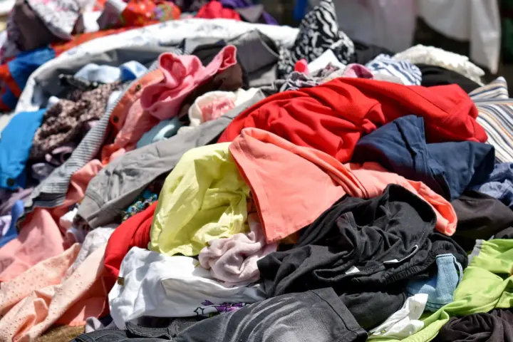 Pile of discarded clothes and textiles representing fashion waste and unsold apparel amid new EU rules restricting the destruction of unsold garments.