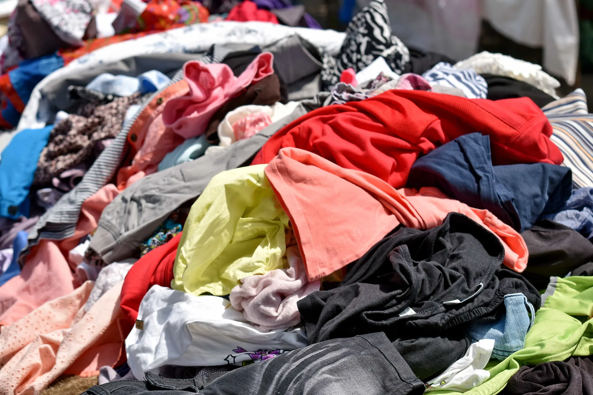 Pile of unsold and discarded clothing representing the fashion industry's overproduction and textile waste crisis, addressed by the EU ESPR unsold goods ban July 2026