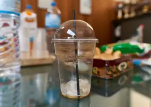 Disposable clear plastic cup with lid and straw on a table, illustrating single-use plastic packaging commonly associated with polypropylene waste streams and recycling challenges.