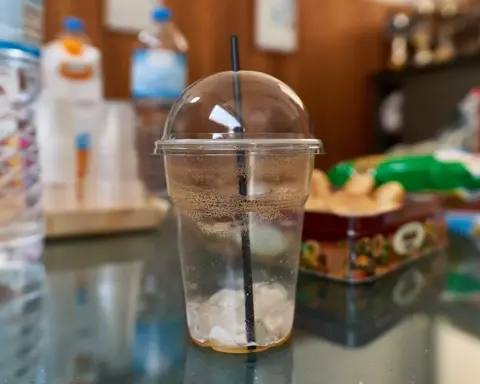 Disposable clear plastic cup with lid and straw on a table, illustrating single-use plastic packaging commonly associated with polypropylene waste streams and recycling challenges.