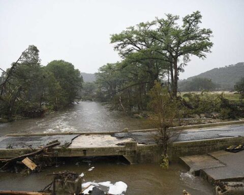 Floodwaters inundate a Texas community, with homes and vehicles partially submerged.