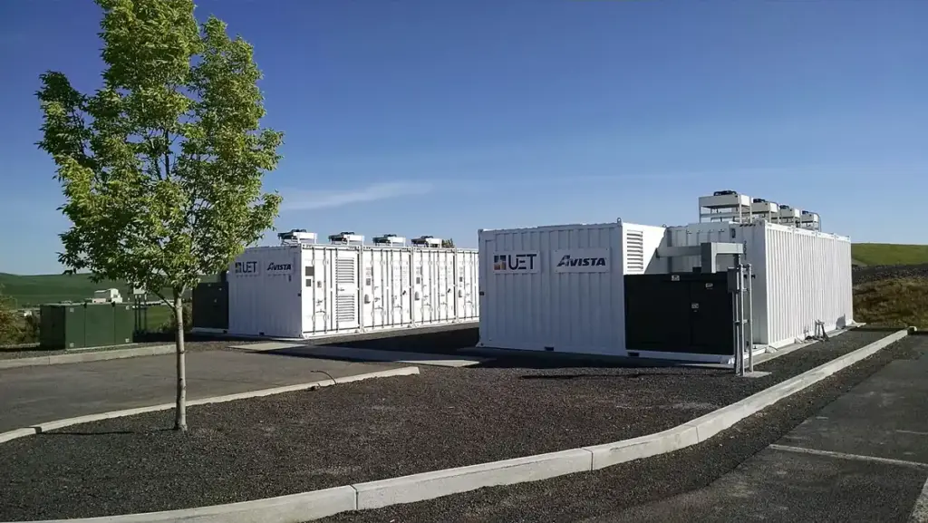 White containerised battery energy storage containers with UET and Avista branding, cooling units on roof.