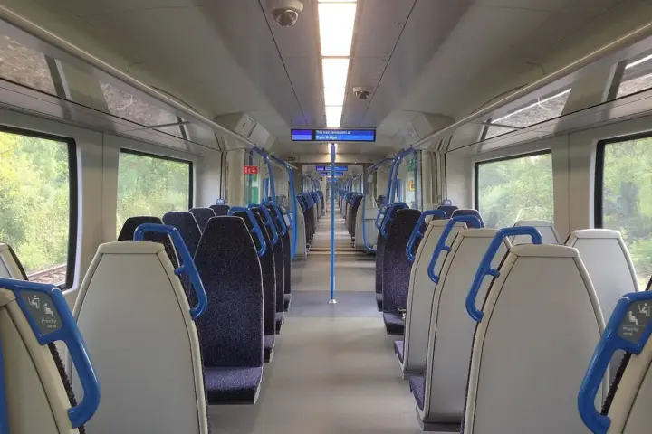 Interior of a Thameslink Class 700 train carriage with blue seats and priority-seat signage.