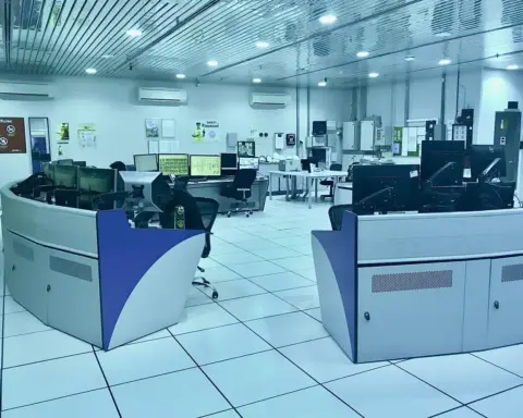 Industrial SCADA control room with rows of operator monitors displaying system data.