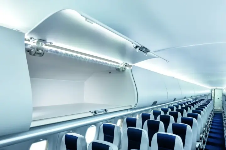 Airliner cabin interior showing overhead baggage compartments above passenger seats.