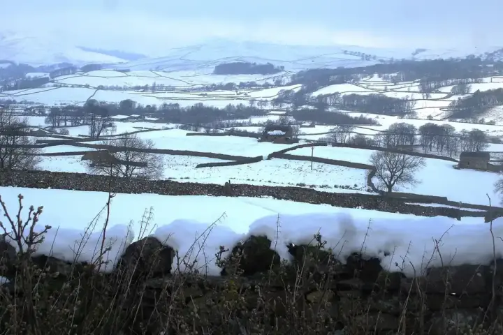 Snow-covered rural landscape in Wensleydale, England.