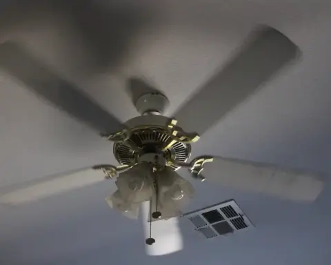 A spinning ceiling fan on a textured ceiling