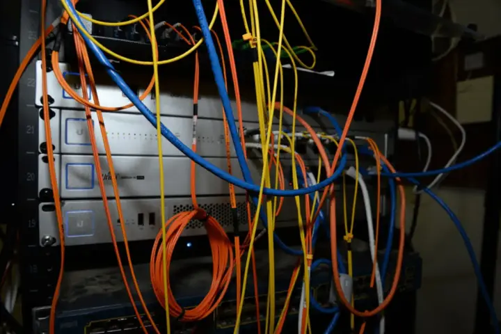 Photograph of a network server rack filled with switches and colored cabling, representing enterprise IT infrastructure.