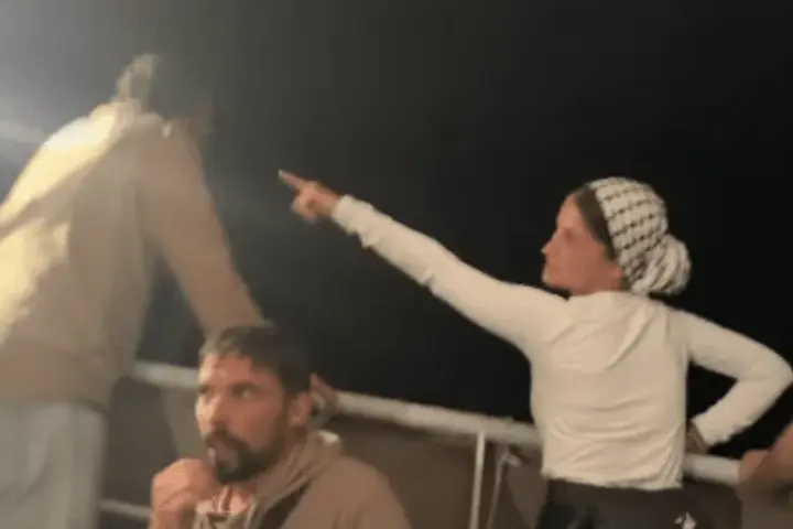 Activists aboard a Gaza aid vessel pointing at surveillance drones overhead.