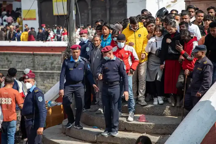 Police personnel regulating a dense crowd of Hindu devotees on temple steps during a Shiva festival