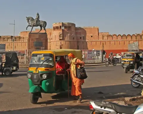 Green and yellow auto-rickshaw picking up a passenger outside Junagarh Fort in Bikaner, Rajasthan.