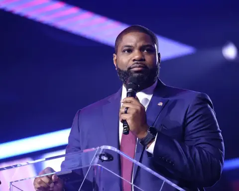 U.S. Representative Byron Donalds speaking at a podium with an American flag pin.
