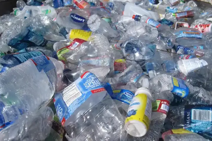 Stack of blue and plastic bottles and containers at a recycling collection point
