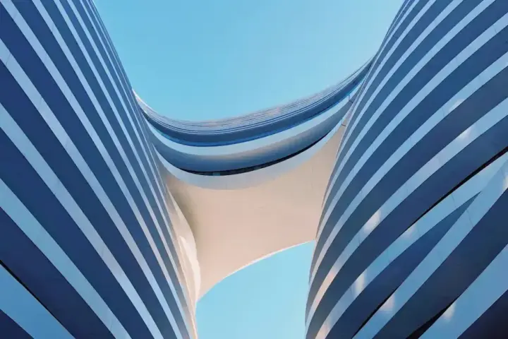 Modern glass building facade reflecting blue sky with geometric architectural design