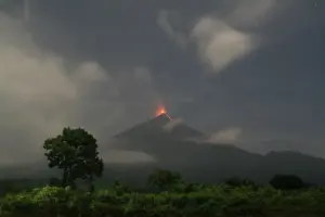 Volcan de Fuego cone silhouetted at night with glowing lava at its summit