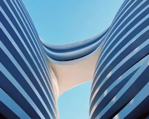 Modern glass building facade reflecting blue sky with geometric architectural design