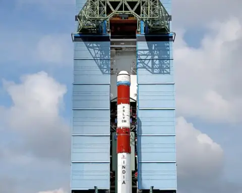 ISRO's PSLV-C60 launch vehicle on the launch pad at Satish Dhawan Space Centre, Sriharikota, with ground staff in high-visibility vests behind a safety fence.