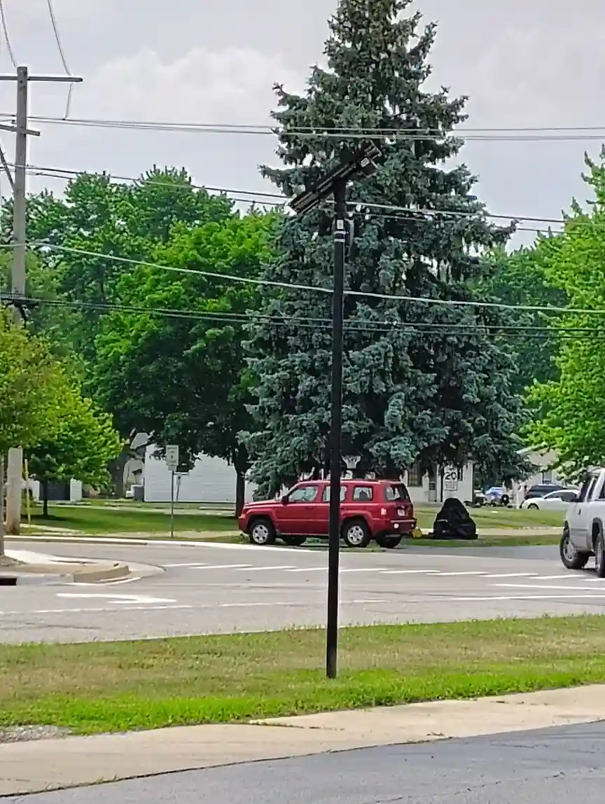 A Flock Safety automated license-plate reader camera mounted on a pole in a quiet residential neighborhood.