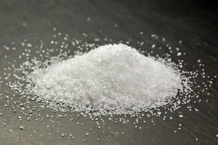 White crystalline erythritol sugar substitute powder on dark stone surface representing artificial sweetener health research