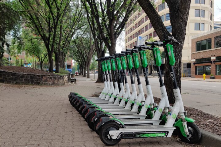 Several Lime shared e-scooters parked on a city pavement