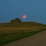 Partial lunar eclipse with Moon appearing reddish in Earth's umbral shadow, astrophotography by Evelyn Berg