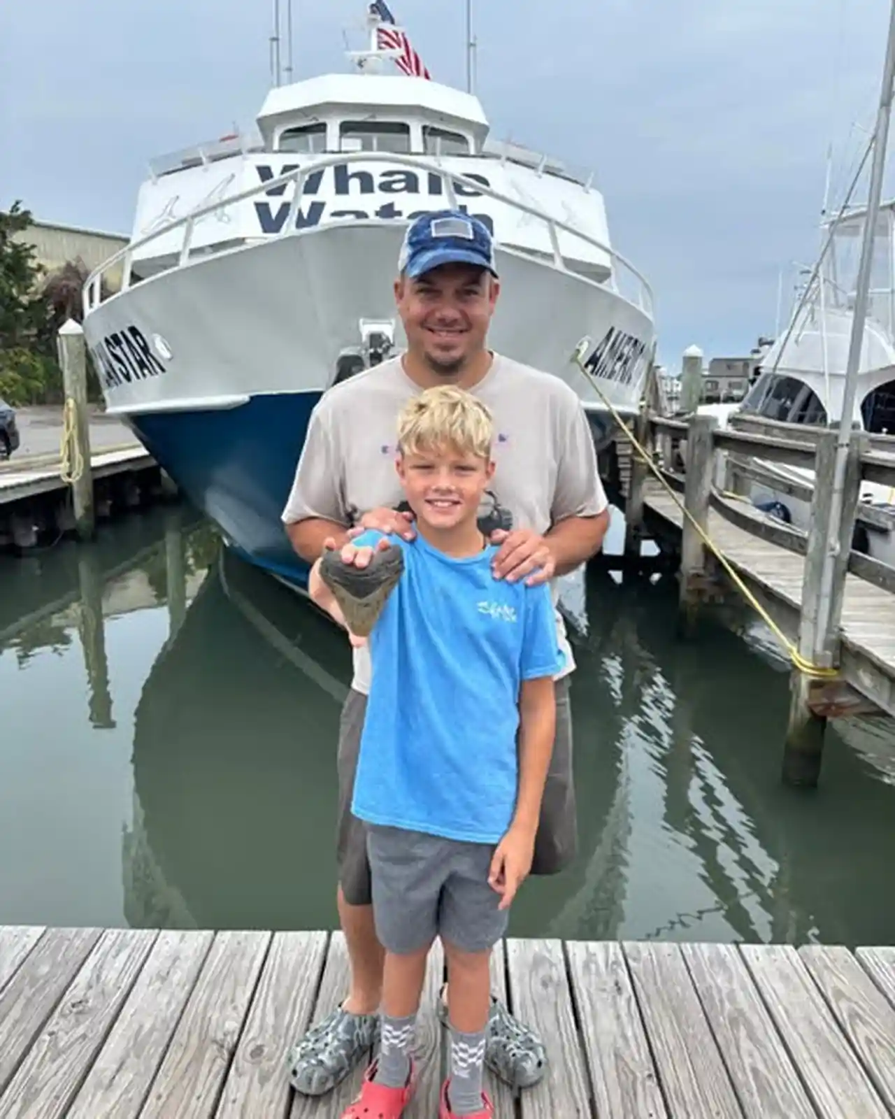 Bowers family on the dock after the megalodon tooth find A Pennsylvania father and his son pose on a wooden dock in front of the Cape May Whale Watch boat 'Water Star' after finding a fossilized megalodon tooth at the Jersey Shore.