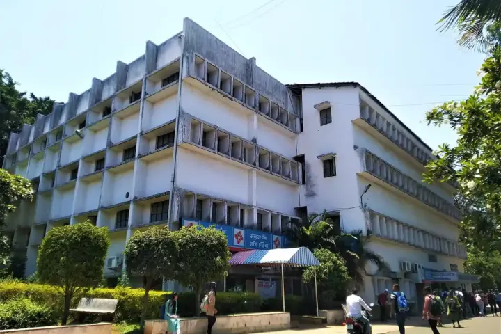 Multi-storey engineering college building in India with students carrying backpacks walking past the entrance.
