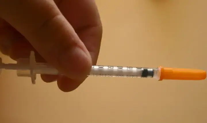 Close-up of an insulin syringe being held before injection representing diabetes treatment and GLP-1 medication use