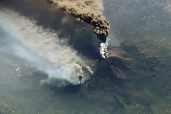 Mount Etna volcanic eruption seen from the International Space Station, showing ash plume reaching 7,300 meters