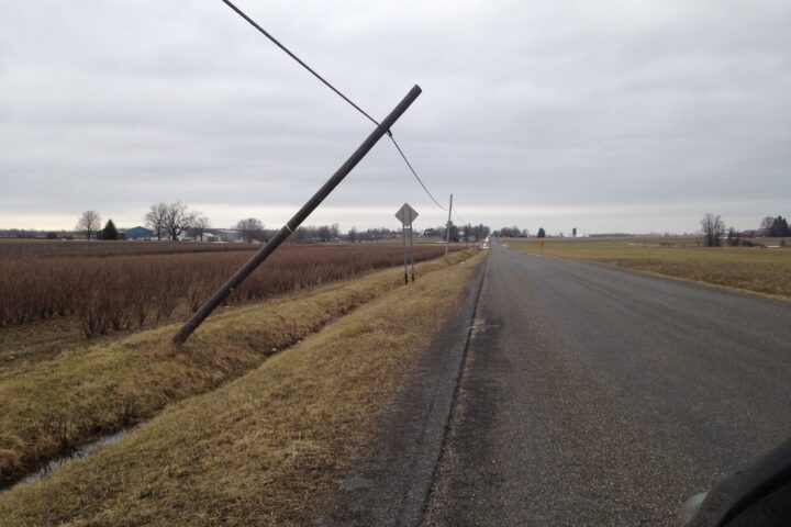 Utility pole leaning after a storm, representing power-grid damage