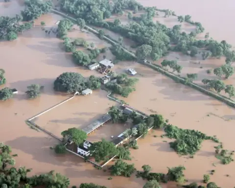 Aerial photograph of flooded villages in Balasore, Odisha, with homes and farmland submerged under muddy brown river water.