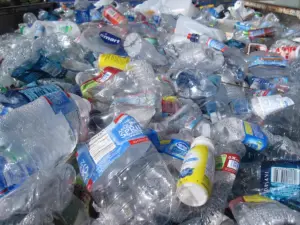 Stacks of discarded plastic and glass bottles at a recycling collection point, symbolizing the chemical contamination cycling through water systems.